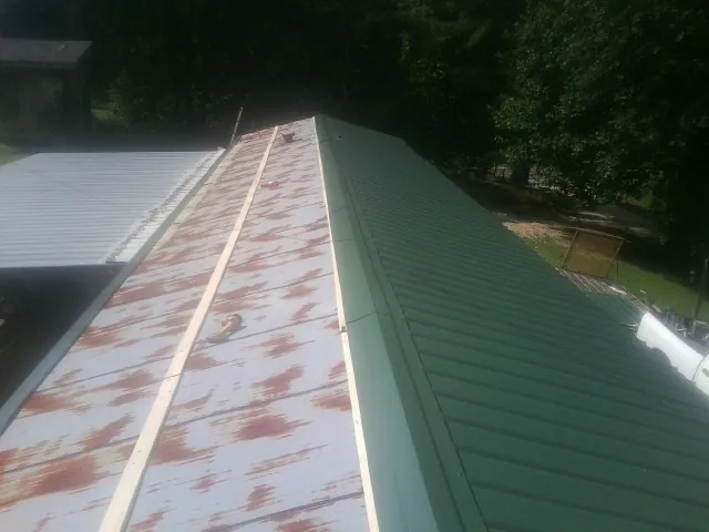 Old rusted panels beside newly installed green metal roofing — Wind Damage Roof Repair by Roofing Brothers in Talmage