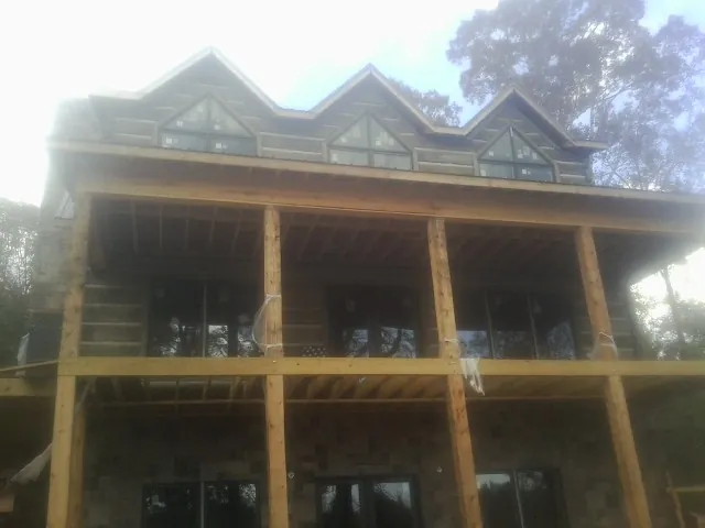 Dormers and porch framing on a large log home under construction — Roof Coating work by our crew in Talmage